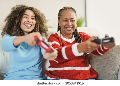 African American Mother And Mixed Race Adult Daughter Having Fun Playing Video Games At Home