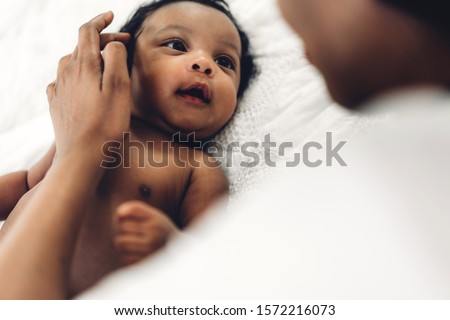 African american mother playing with adorable little african american baby in a white bedroom.Love of black family concept