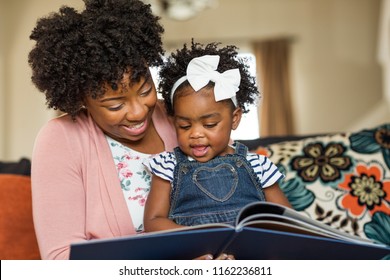 African American mother reading a book to her little girl.