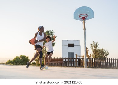 African American Mother And Son Playing Basketball In Sports Court At Park