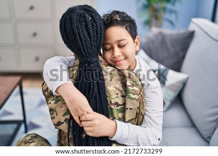 African american mother and son wearing soldier uniform hugging each other at home