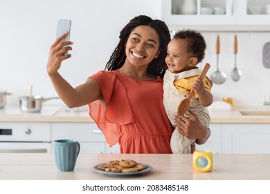 African American Mother Taking Selfie With Her Little Baby On Smartphone In Kitchen Interior, Happy Black Woman Making Photos With Cute Infant Child At Home, Enjoying Spending Time Together