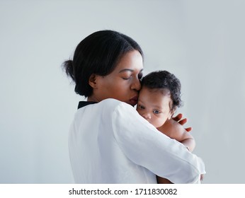 African American Mum Is Comforting A Baby On A White Background.