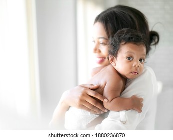 African American Mum Is Comforting A Baby On A White Room.