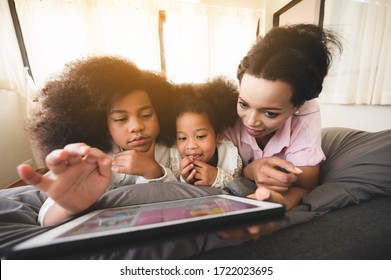 African American mum and daughter are watching the tablet relaxed in the house. Ideas about staying at home with family
