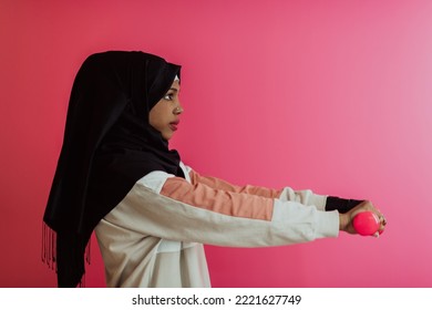 African American muslim woman promotes a healthy life, holding dumbbells in her hands
