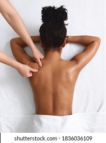 African American Naked Woman Getting Relaxing Back Massage On White, View Above. Top View Of Black Lady Having Healing Body Massage From Unrecognizable Female Therapist At Modern Newest Spa