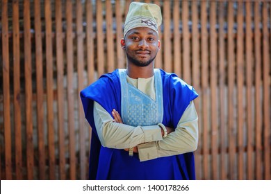 African American in national dress stands in front of a wooden background / copy space