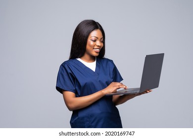 African American Nurse Or Doctor Woman Wearing Medical Form Holding Laptop Isolated Against White Background