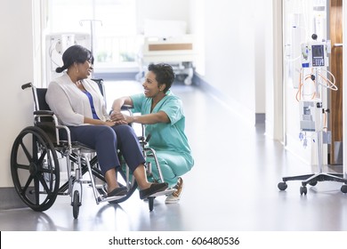 African American nurse in scrubs with patient in hospital wheelchair in corridor of specialist care clinic - Powered by Shutterstock