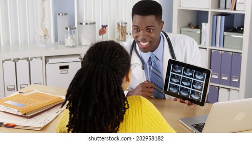 African American OBGYN using tablet to show ultrasound to patient at desk