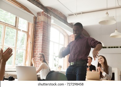 African american office worker dancing surrounded by coworkers. Happy entrepreneur performing victory dance, celebrating great achievement at work. Team of coworkers cheering him by clapping hands.  - Powered by Shutterstock