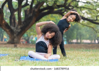 African american older sister and younger sister practicing yoga in the park outdoor - Powered by Shutterstock