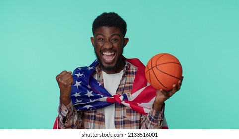 African American One Young Man 20s Sportsman Basketball Fan In Checkered Shirt Holding American USA Flag Doing Winner Gesture, Dancing Isolated On Blue Background. Workout Sport Motivation Lifestyle