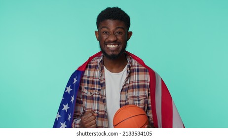 African American One Young Man 20s Sportsman Basketball Fan In Checkered Shirt Holding American USA Flag Doing Winner Gesture, Dancing Isolated On Blue Background. Workout Sport Motivation Lifestyle