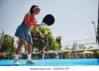 African American paddle tennis player serving the ball during the match on outdoor court. Copy space. - Powered by Shutterstock