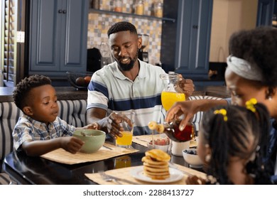 African american parents and children having pancakes and juice on dining table at home. Unaltered, family, togetherness, childhood, breakfast, food, fresh and morning concept. - Powered by Shutterstock