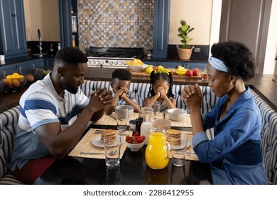 African american parents and children saying grace before breakfast at dining table during morning. Unaltered, family, togetherness, childhood, gratitude, prayer, food, religion and home concept. - Powered by Shutterstock