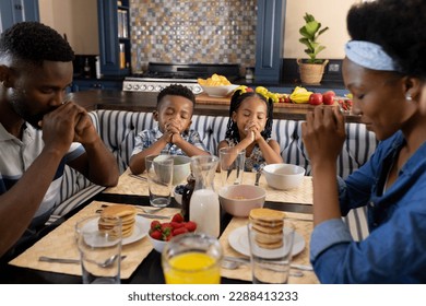 African american parents and children saying grace at dining table before breakfast in morning. Unaltered, family, togetherness, childhood, gratitude, food, prayer, religion and home concept. - Powered by Shutterstock