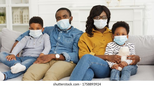 African American parents and cute small kids wearing protective masks at home. Stop the virus and epidemic diseases.