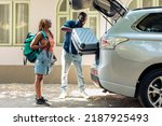 African american partners travelling by vehicle, putting luggage and baggage in trunk to leave on summer holiday. People in relationship going on vacation trip with trolley and travel bags.