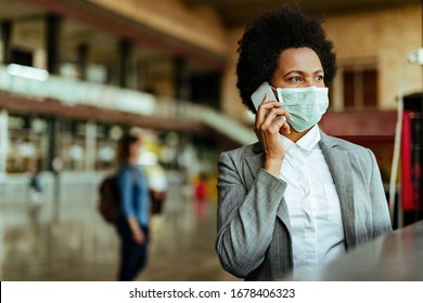 African American passenger communicating over cell phone while wearing face mask during virus epidemic at railroad station.  - Powered by Shutterstock