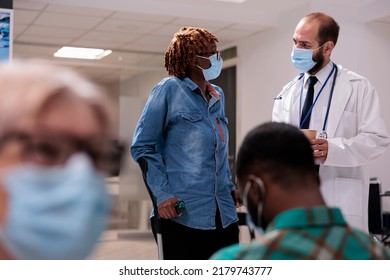 African American Patient With Crutches In Hospital Lobby, Talking To Male Doctor About Healthcare And Recovery. Woman With Chronic Disability And Impairment Doing Checkup Visit.