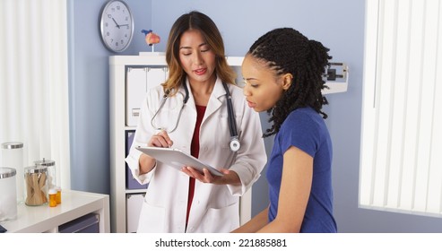 African American patient explaining issues to Asian doctor using tablet