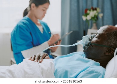 African American patient resting in hospital bed while being attended by Latin nurse writing observations on clipboard in brightly lit room with flowers in background - Powered by Shutterstock