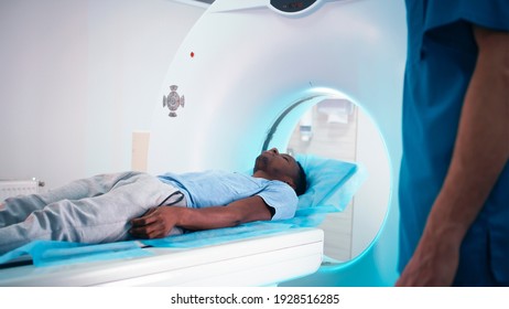 African American patient taking seat and asking questions about CT scan to crop medical practitioner after examination procedure in modern hospital