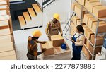 African american people packing products in boxes before doing quality control to ship merchandise. Warehouse employees checking inventory and stock logistics, retail shipment. Handheld shot.