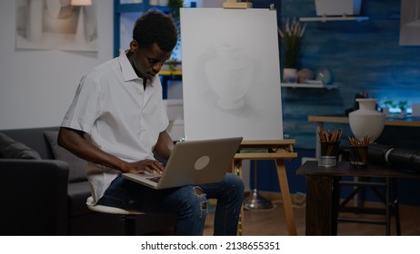 African American Person Using Laptop For New Inspiration Sitting In Artwork Room At Home. Black Young Artist With Technology And Device For Modern Masterpiece Creation And Drawing