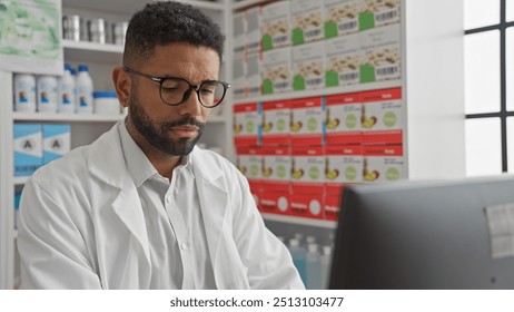 African american pharmacist reviewing data on a computer in a modern pharmacy interior - Powered by Shutterstock