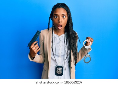 African American Police Woman Holding Gun And Handcuffs Afraid And Shocked With Surprise And Amazed Expression, Fear And Excited Face. 