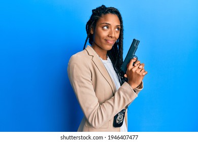 African American Police Woman Holding Gun Smiling Looking To The Side And Staring Away Thinking. 