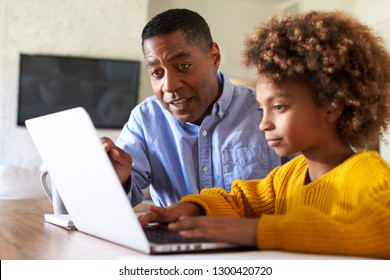 African American pre teen girl black girl using a laptop computer sitting at table in the dining room with her home tutor, close up, selective focus