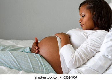 African American pregnant woman looking and holding her stomach.  