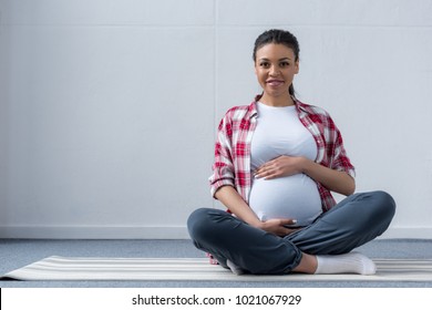 African American Pregnant Woman Sitting On Yoga Mat