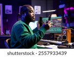 African american producer singer recording audio of his track, adding effects and editing with a stereo console to improve sound quality. Young composer artist performing song on microphone.