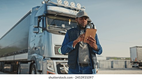 African American professional truck driver setting up navigation for destination. Checking his route on tablet computer and standing by long vehicle. Transportation service. - Powered by Shutterstock