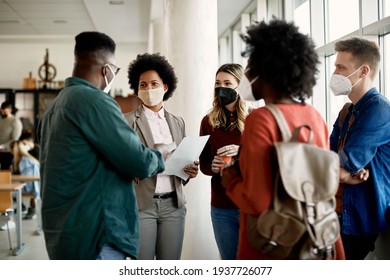 African American Professor Communicating With Her Students At University Hallway. They Are Wearing Face Masks Due To Coronavirus Pandemic.