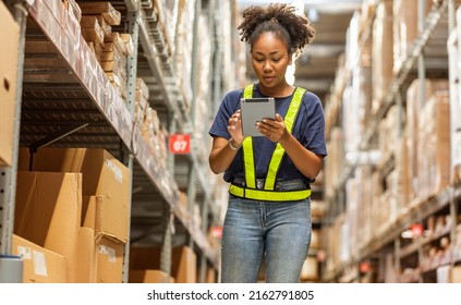 African American Purchasing Worker Wearing A Uniform Holding A Digital Tablet Checks The Inventory Of Raw Materials In A Warehouse.