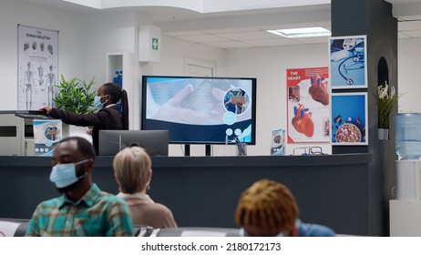 African American Receptionist With Face Mask Working On Appointments To Help With Healthcare Service And Support. Hospital Employee Analyzing Checkup Reports At Reception Desk.