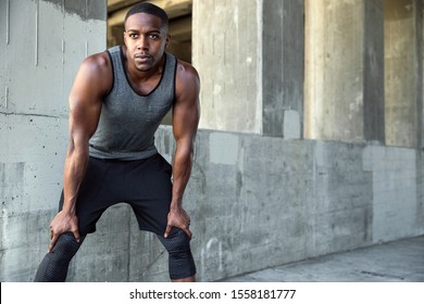 African american runner, resting hands on knees during intense cardio workout downtown, in urban setting - Powered by Shutterstock