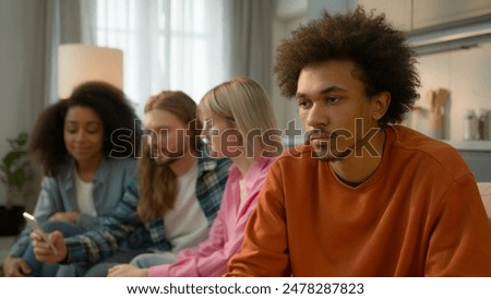African American sad pensive thinking troubled problem frustrated man guy male at home separated ignore multiracial Caucasian multiethnic friends women men mobile phone using addicted laughing talking