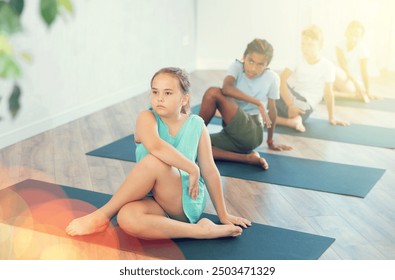 African American schoolboy and his friends meditating in Matsyendra asana in sports club. - Powered by Shutterstock