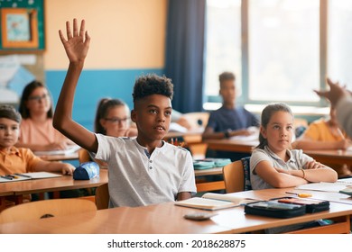 African American schoolboy raising his arm to answer teacher's question during a class at school. - Powered by Shutterstock