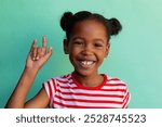 African american schoolgirl doing sign language with hand over blue background at elementary school. Disability, education, childhood, development, learning and elementary school, unaltered.