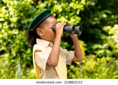 African american scout girl in uniform looking through binoculars in forest. unaltered, girl scout, childhood, exploration, discovery, adventure and scouting. - Powered by Shutterstock