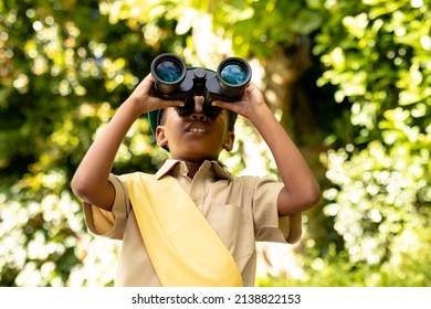 African american scout girl in uniform looking through binoculars while exploring in forest. unaltered, girl scout, childhood, exploration, discovery, adventure and scouting. - Powered by Shutterstock